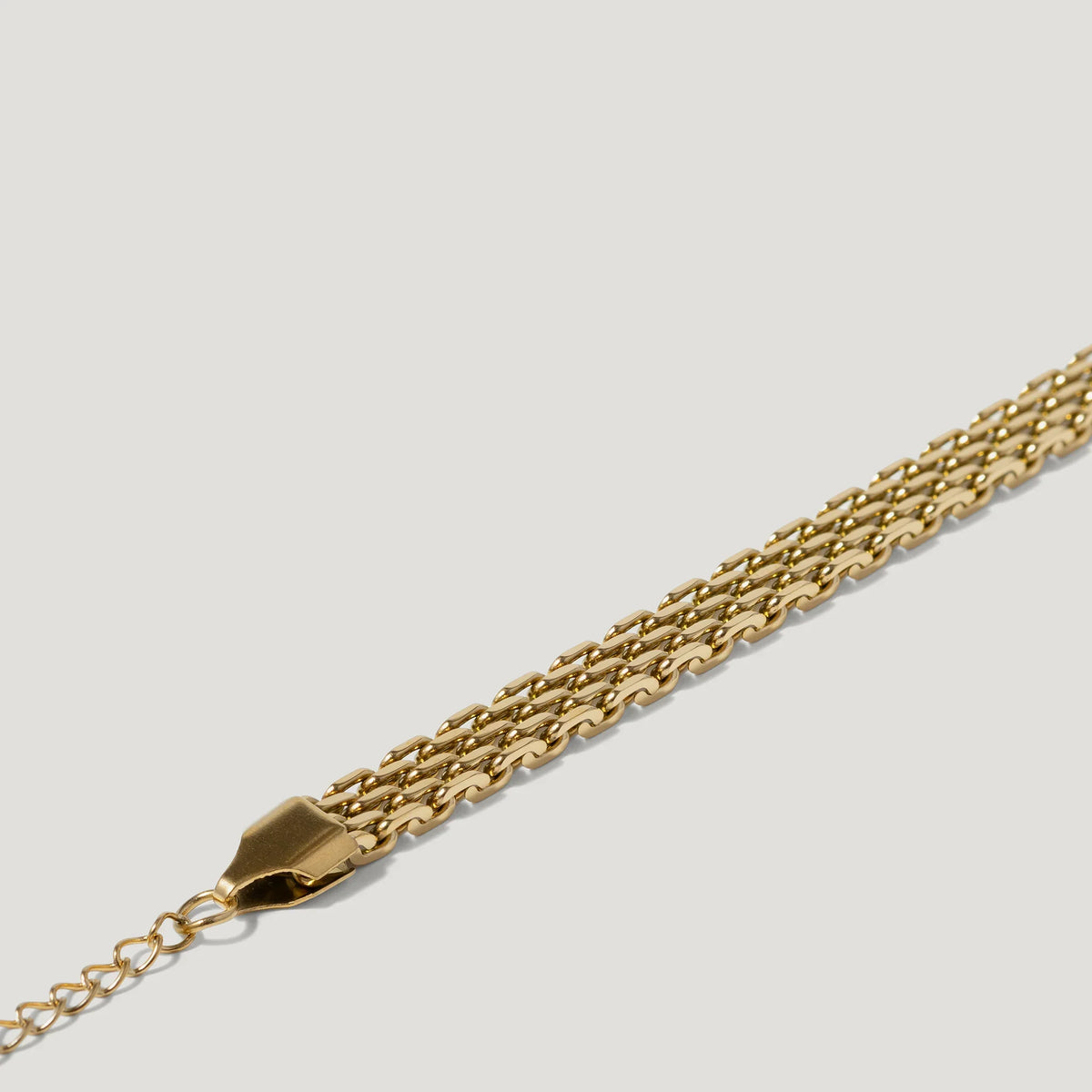 Close-up of a gold chain bracelet with a multi-row link design on white background