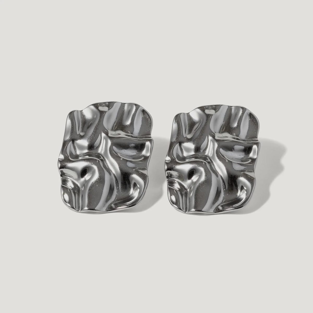 Pair of modern silver sculpted stud earrings with an abstract, wavy design on white background
