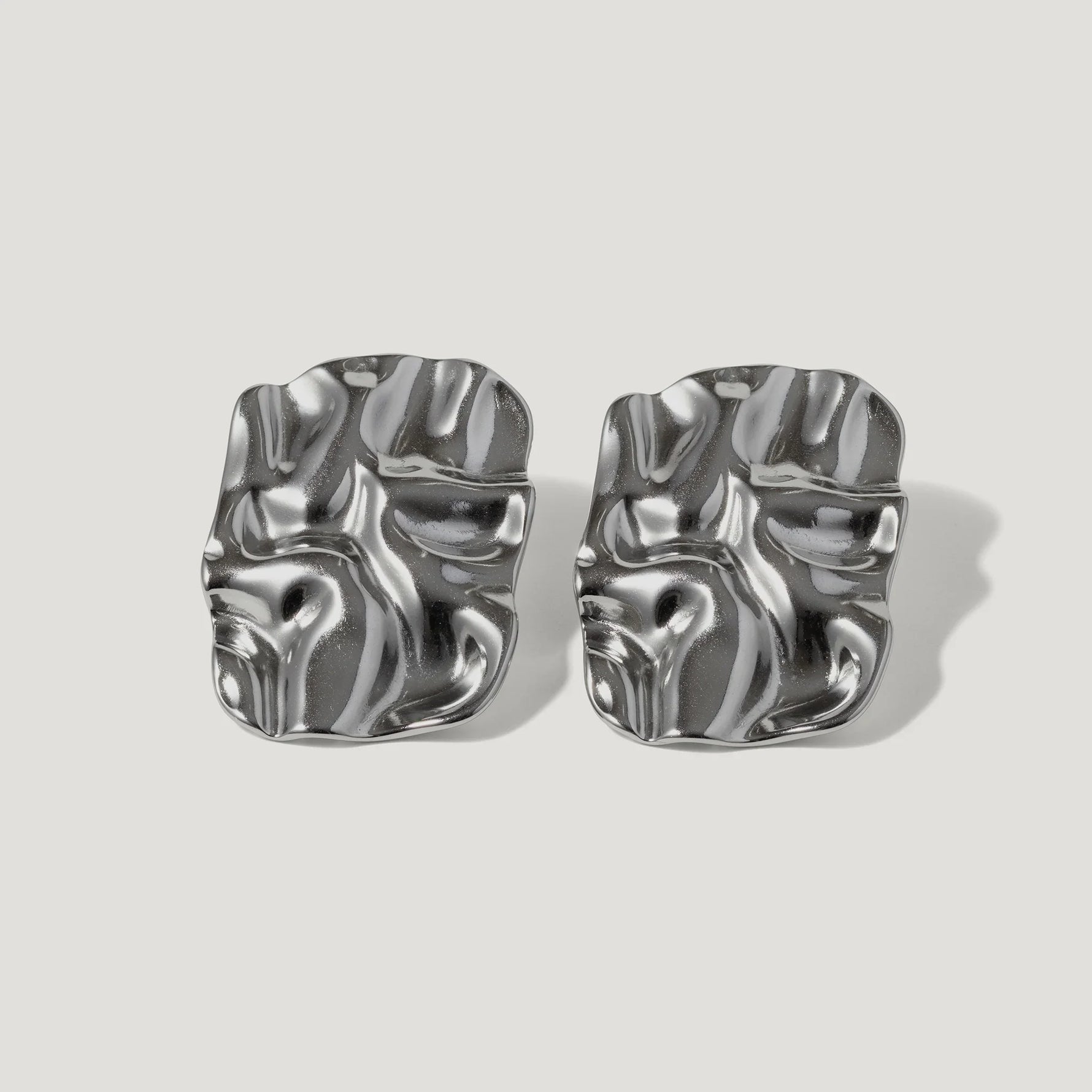 Pair of modern silver sculpted stud earrings with an abstract, wavy design on white background