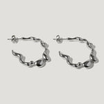 Pair of silver wavy hoop earrings with organic, fluid shapes on a white background