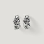 Pair of silver textured hoop earrings with organic, sculptural design on white background