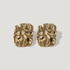 Pair of gold-tone abstract sculpted stud earrings on a light background