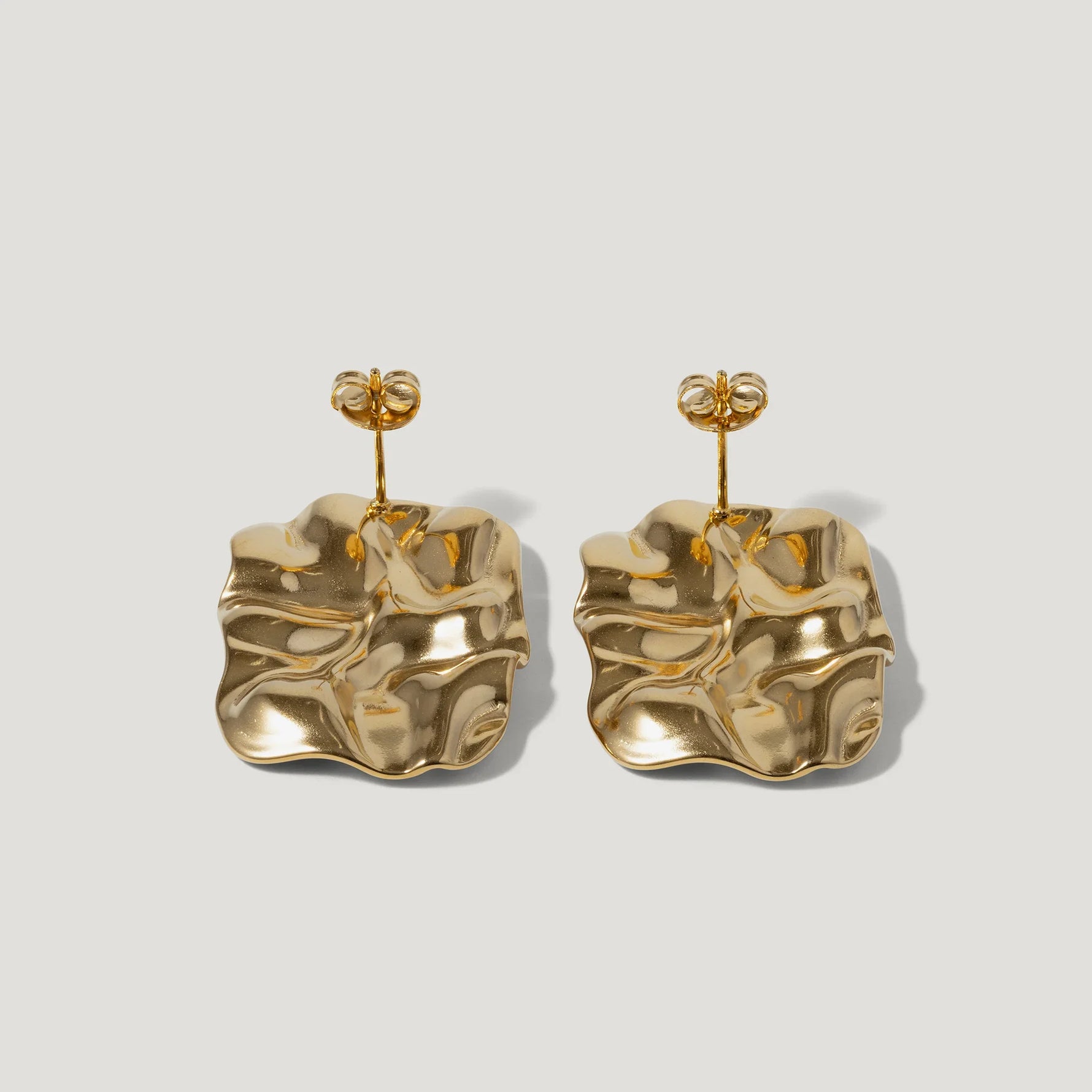 Pair of gold-tone statement earrings with abstract, wavy square design on plain background