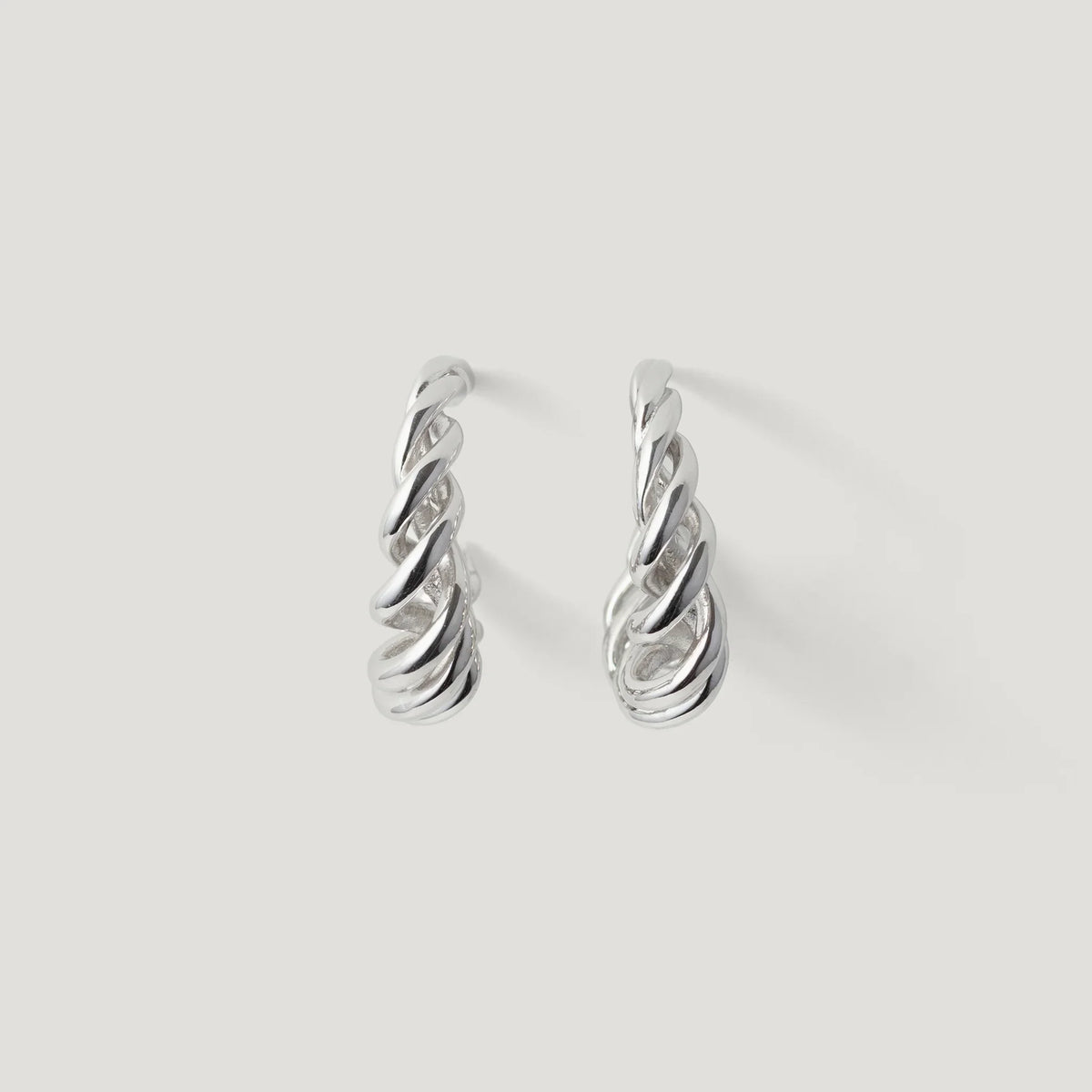 Pair of twisted silver hoop earrings on a plain white background