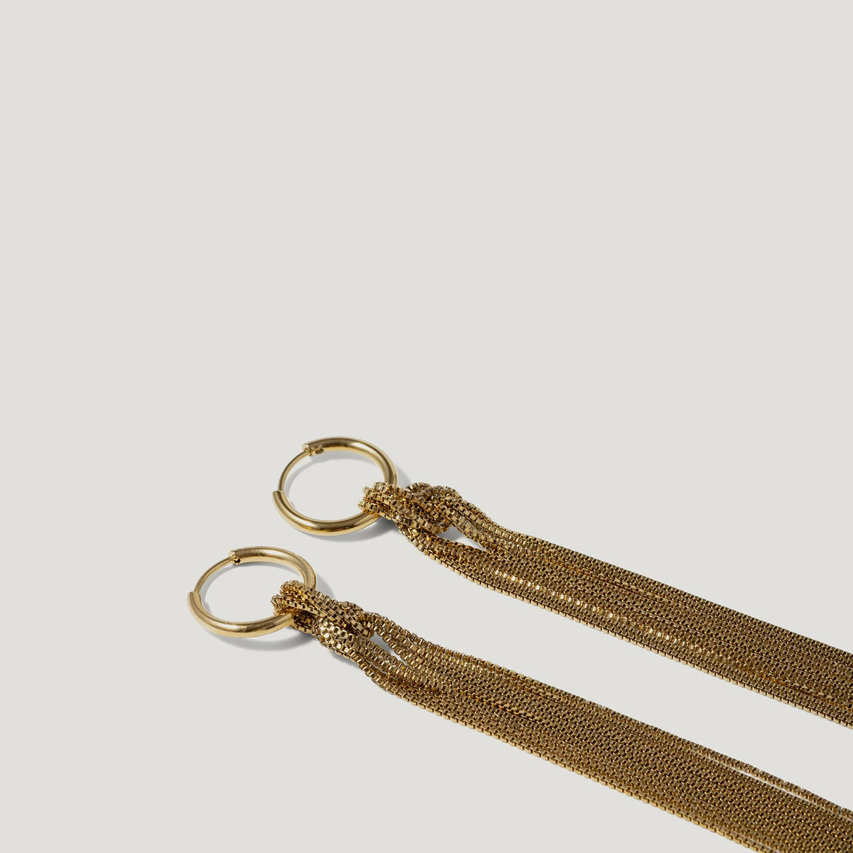 Gold hoop earrings with multiple fine chain tassels on a white background