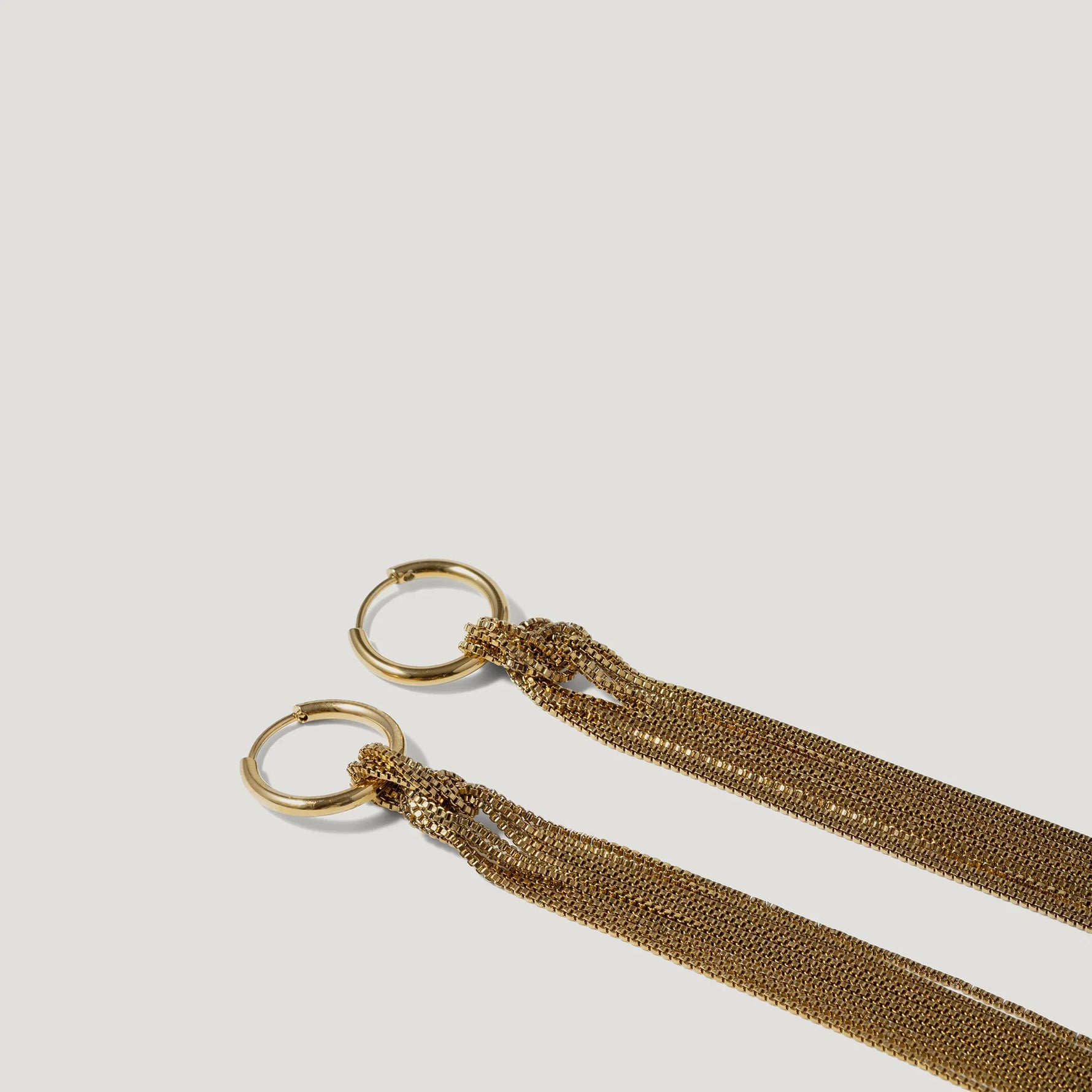 Gold hoop earrings with multiple fine chain tassels on a white background