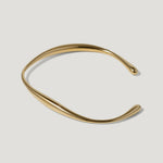 Minimalist gold cuff bracelet with a smooth, curved design on a white background