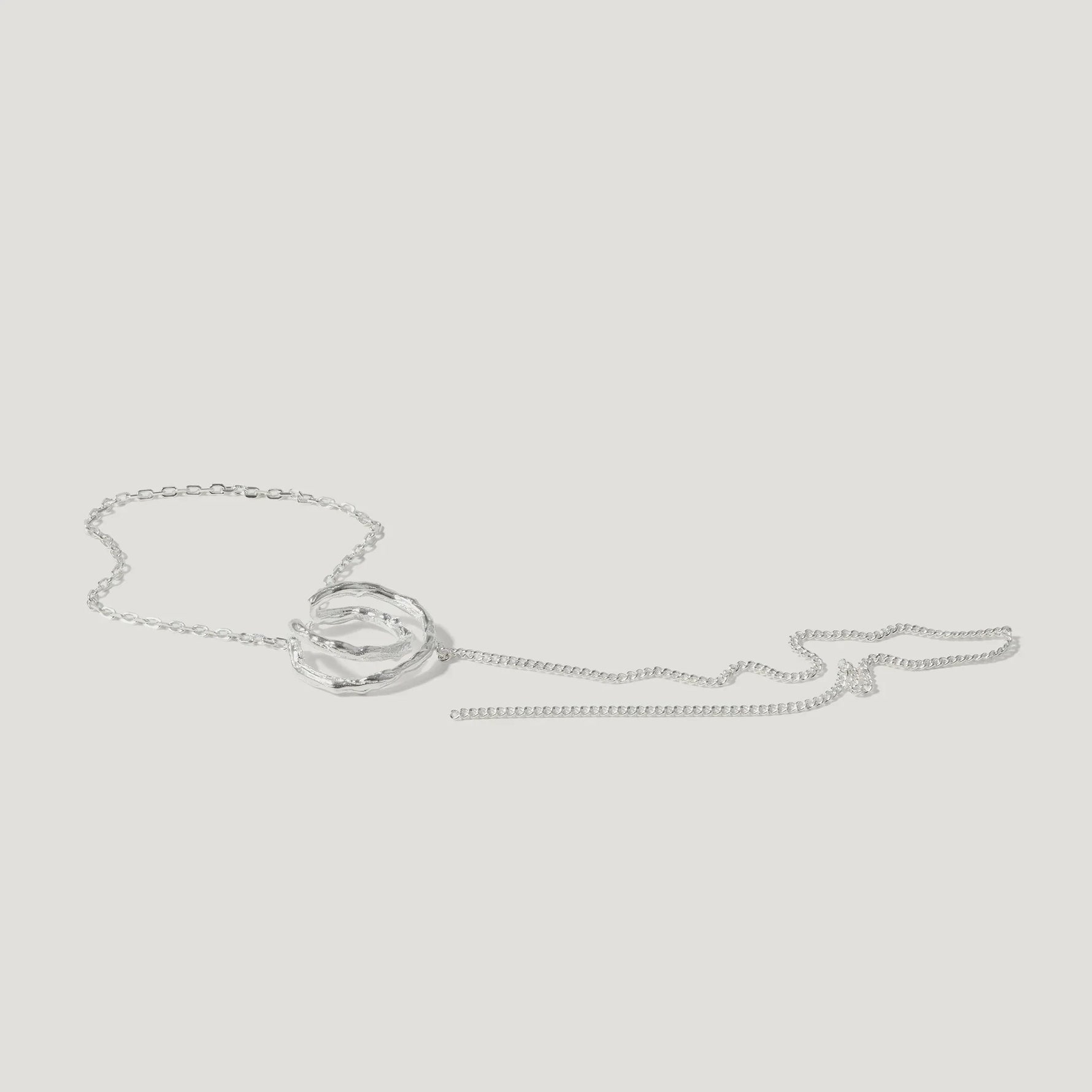 Silver textured pendant necklace with intertwined rings on a white background