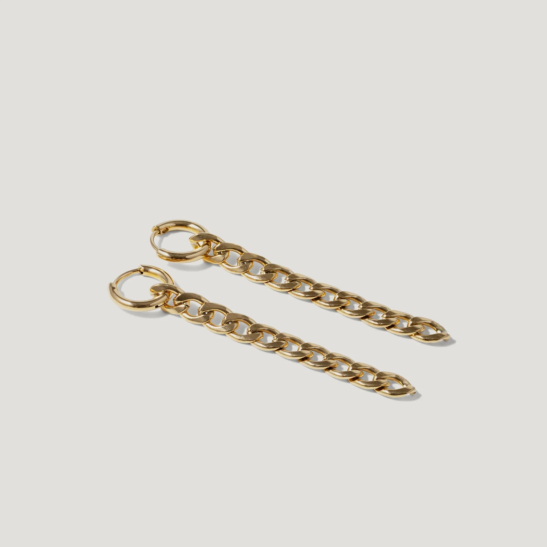 Pair of gold chain link hoop earrings on white background