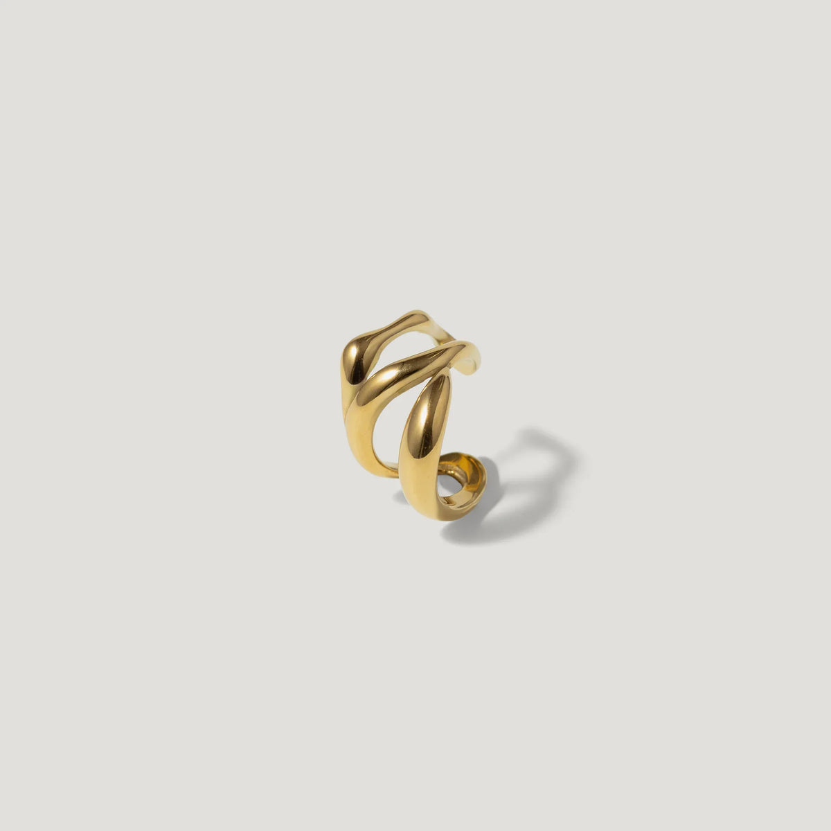 Gold sculptural ring with fluid, organic design on a plain white background