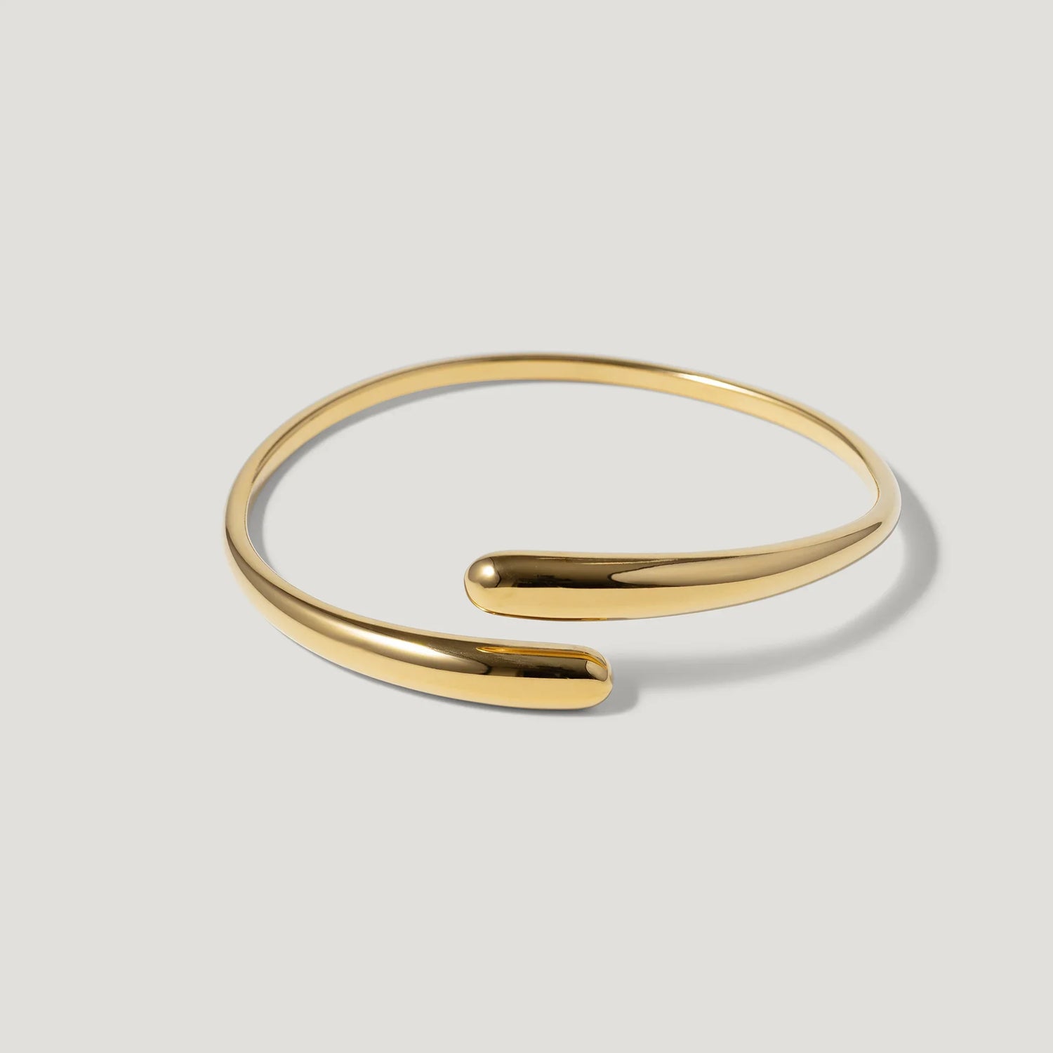 Minimalist gold open cuff bracelet on light background, modern jewelry accessory