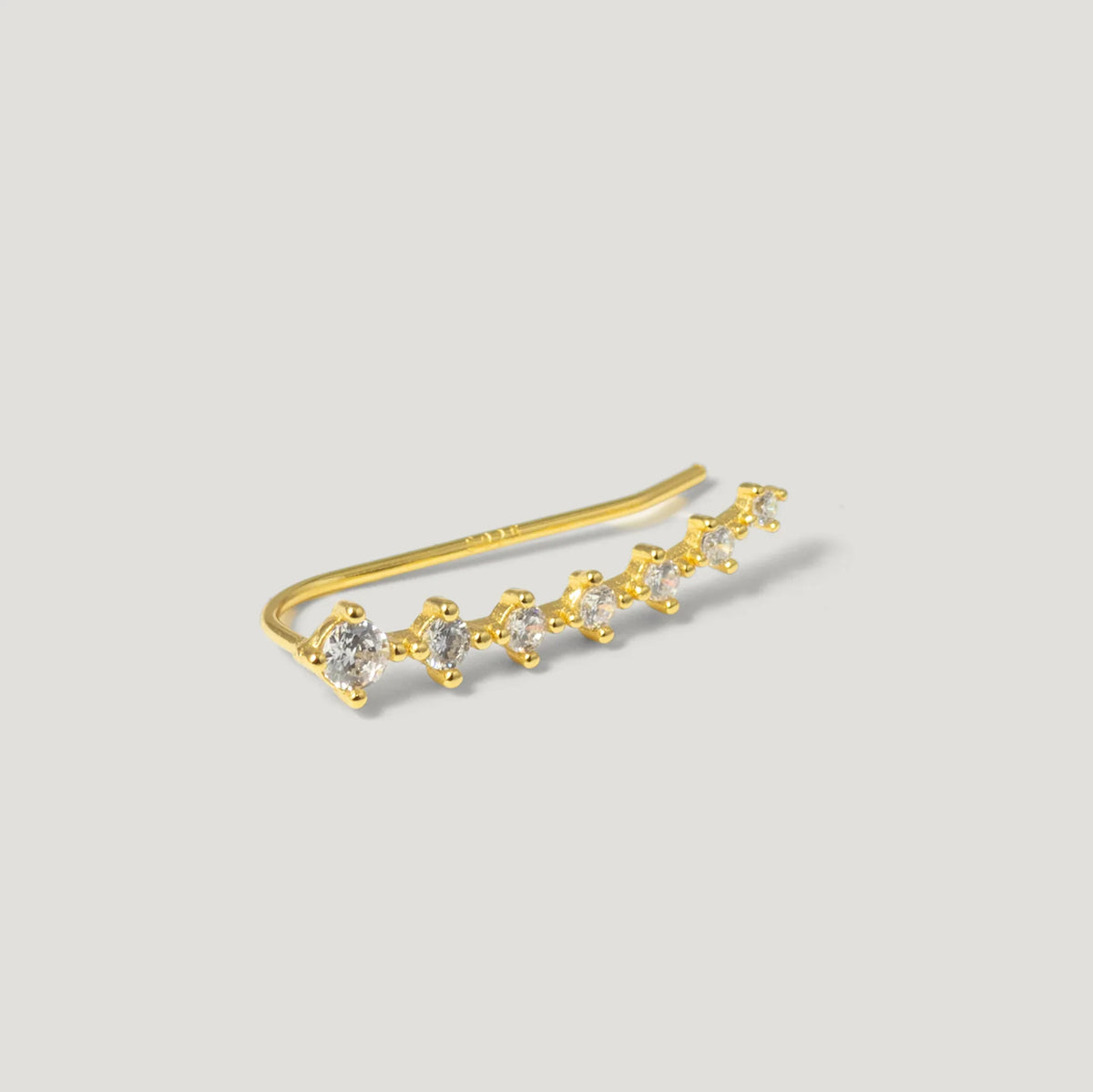 gold ear climber earring with seven round clear gemstones on light background