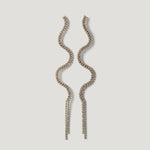 Long wavy gold earrings with clear crystals on a light background