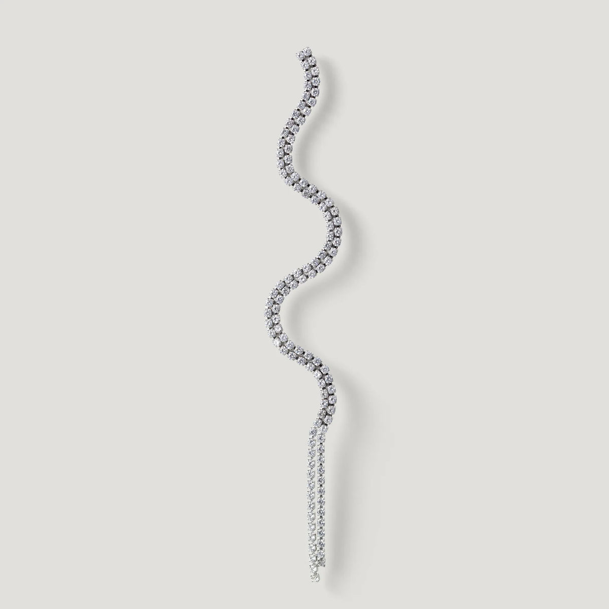 Curved silver diamond earring with wavy design on a light background