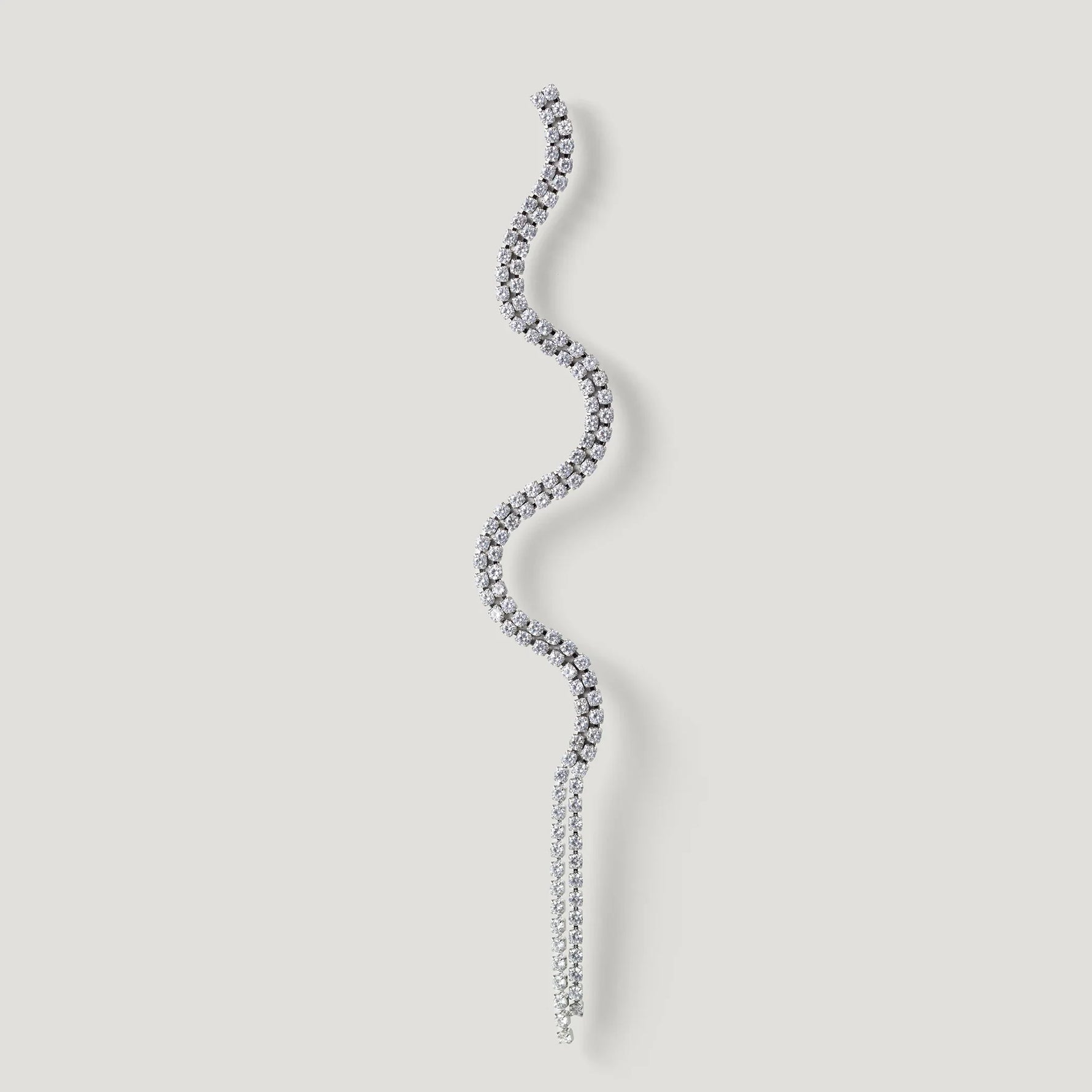 Curved silver diamond earring with wavy design on a light background