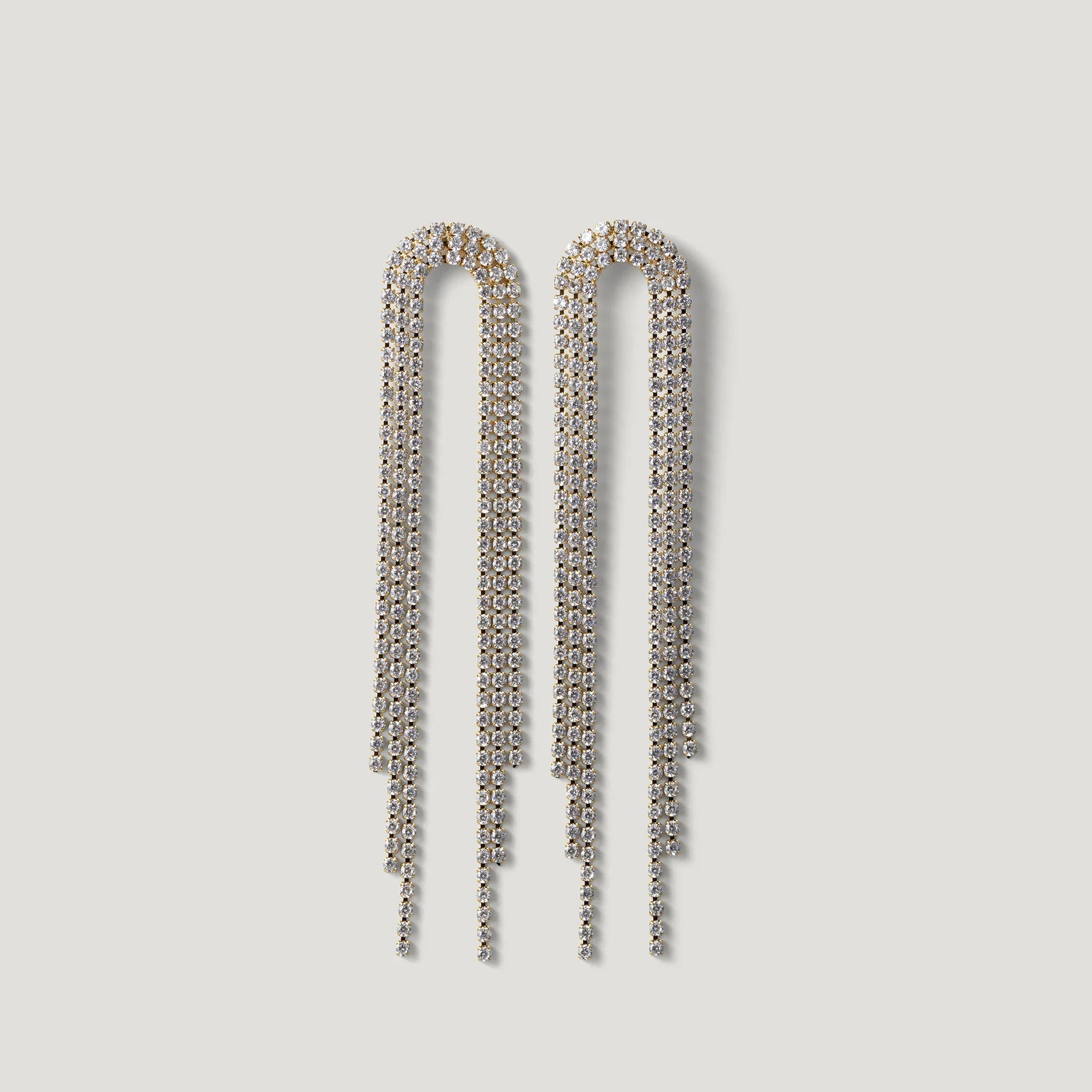 Long crystal fringe drop earrings with gold-tone setting on white background