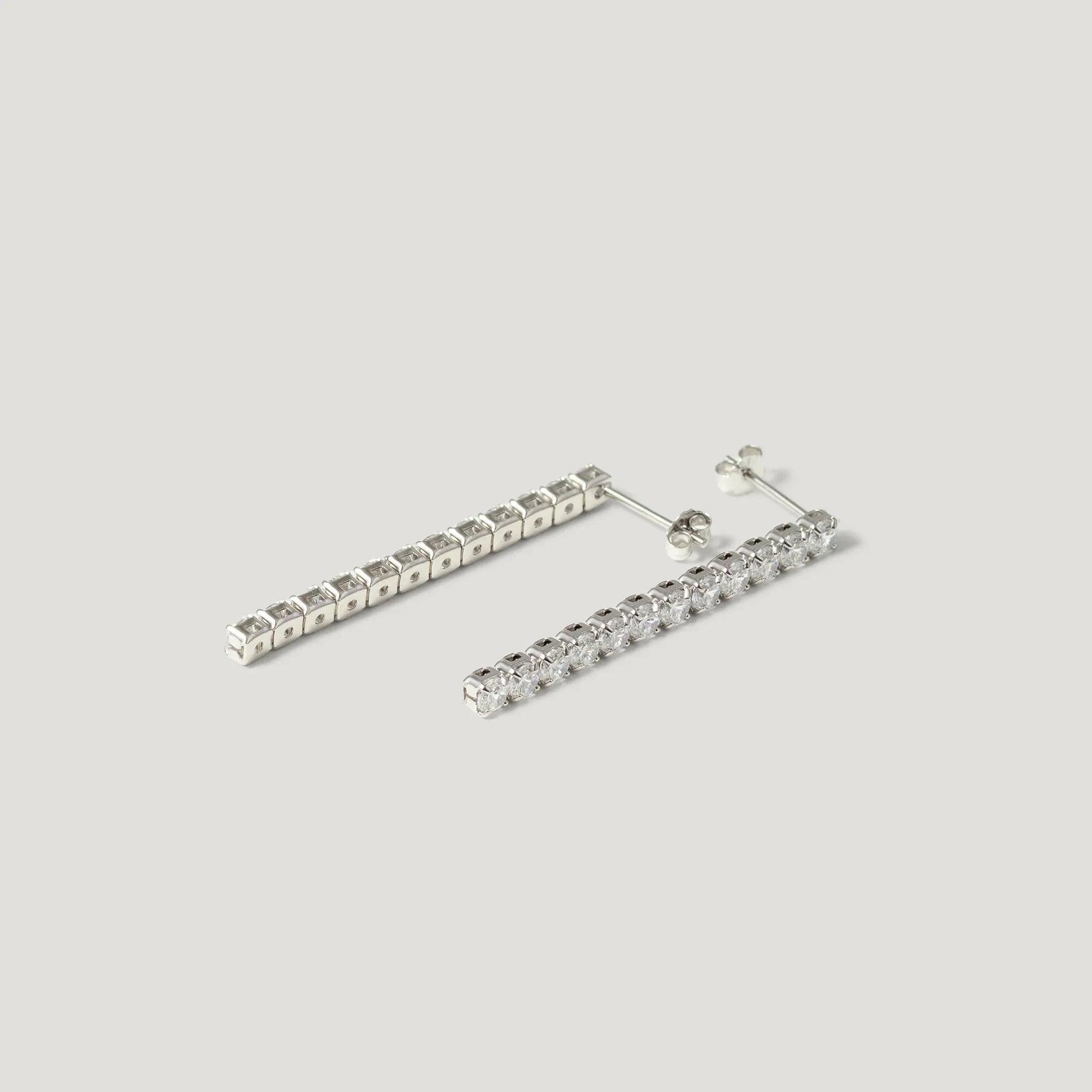 Pair of silver bar stud earrings with clear cubic zirconia stones on white background