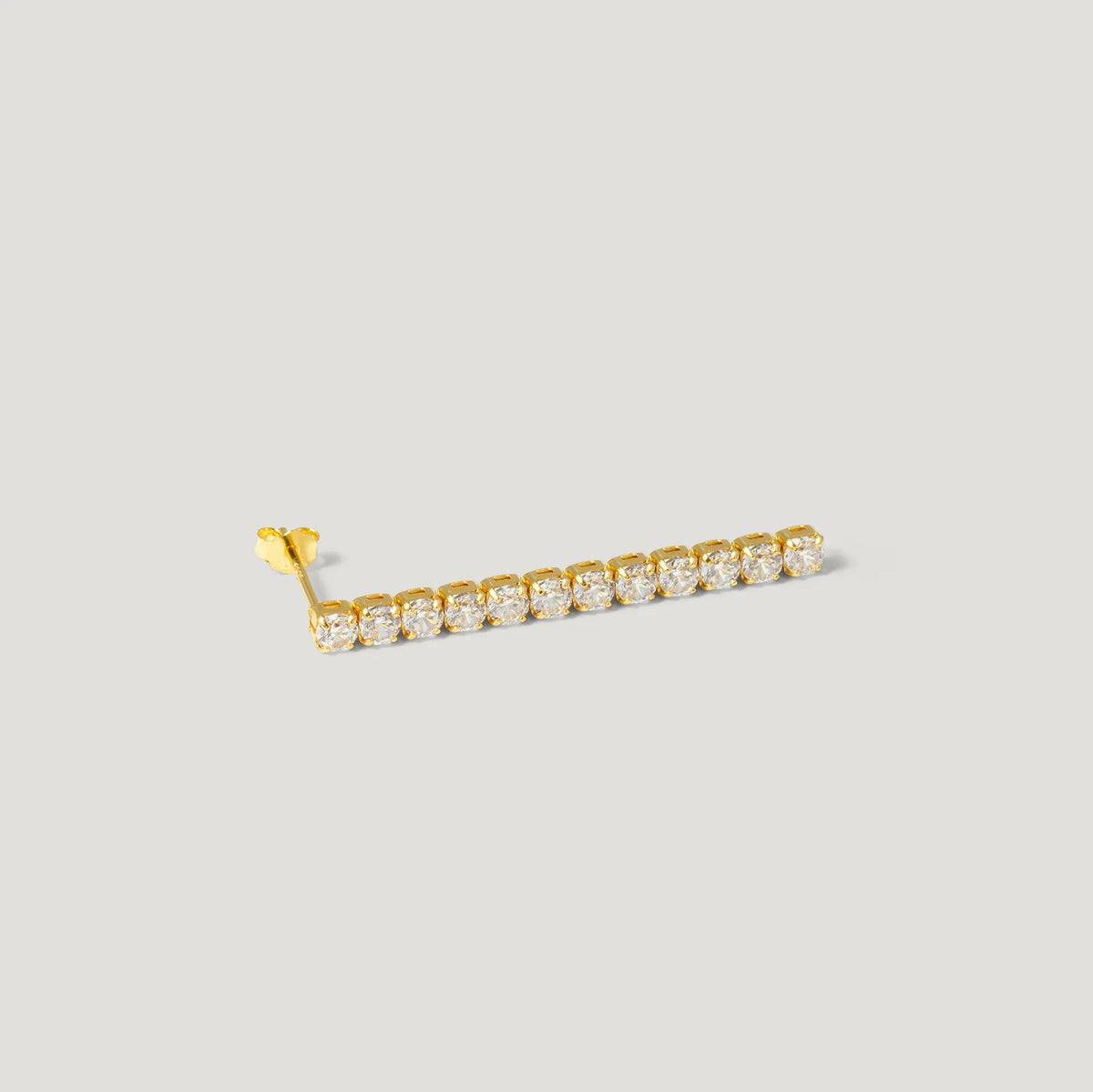 Gold ear climber earring with a row of round sparkling stones on a light background