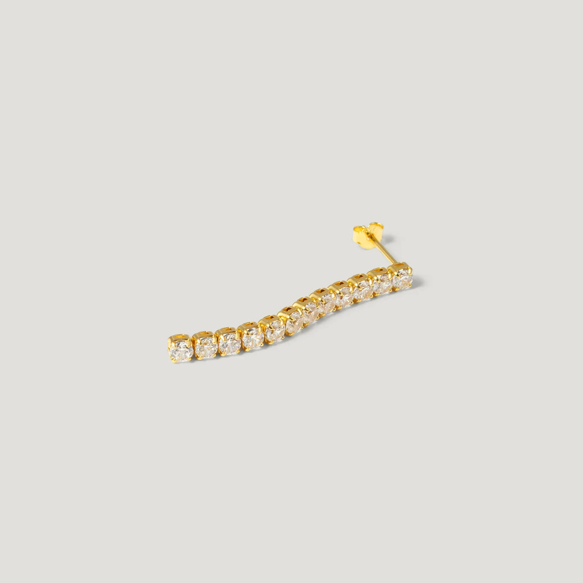 Curved gold ear climber earring with clear gemstones on light background