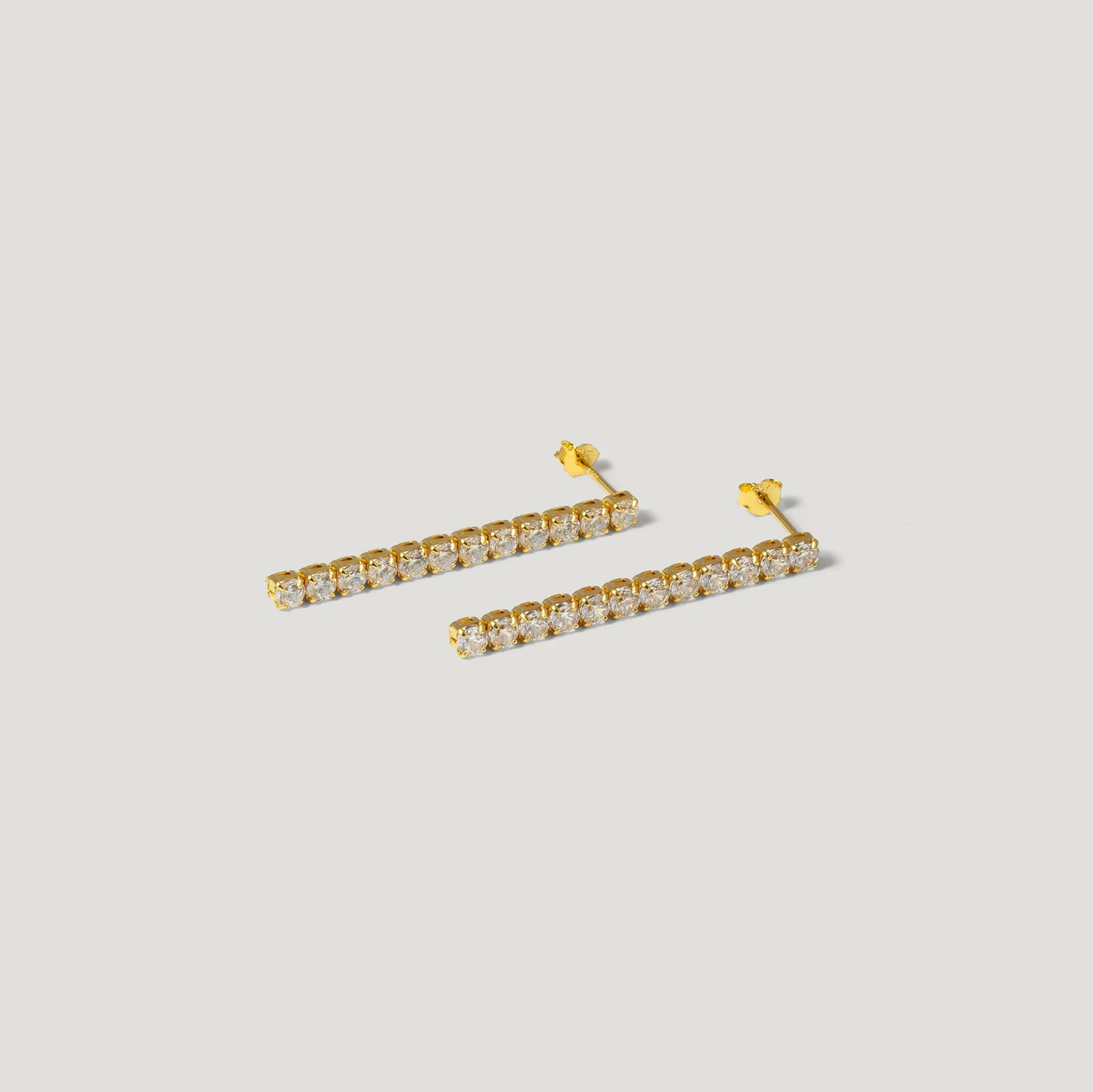 Gold bar stud earrings with clear round gemstones on white background