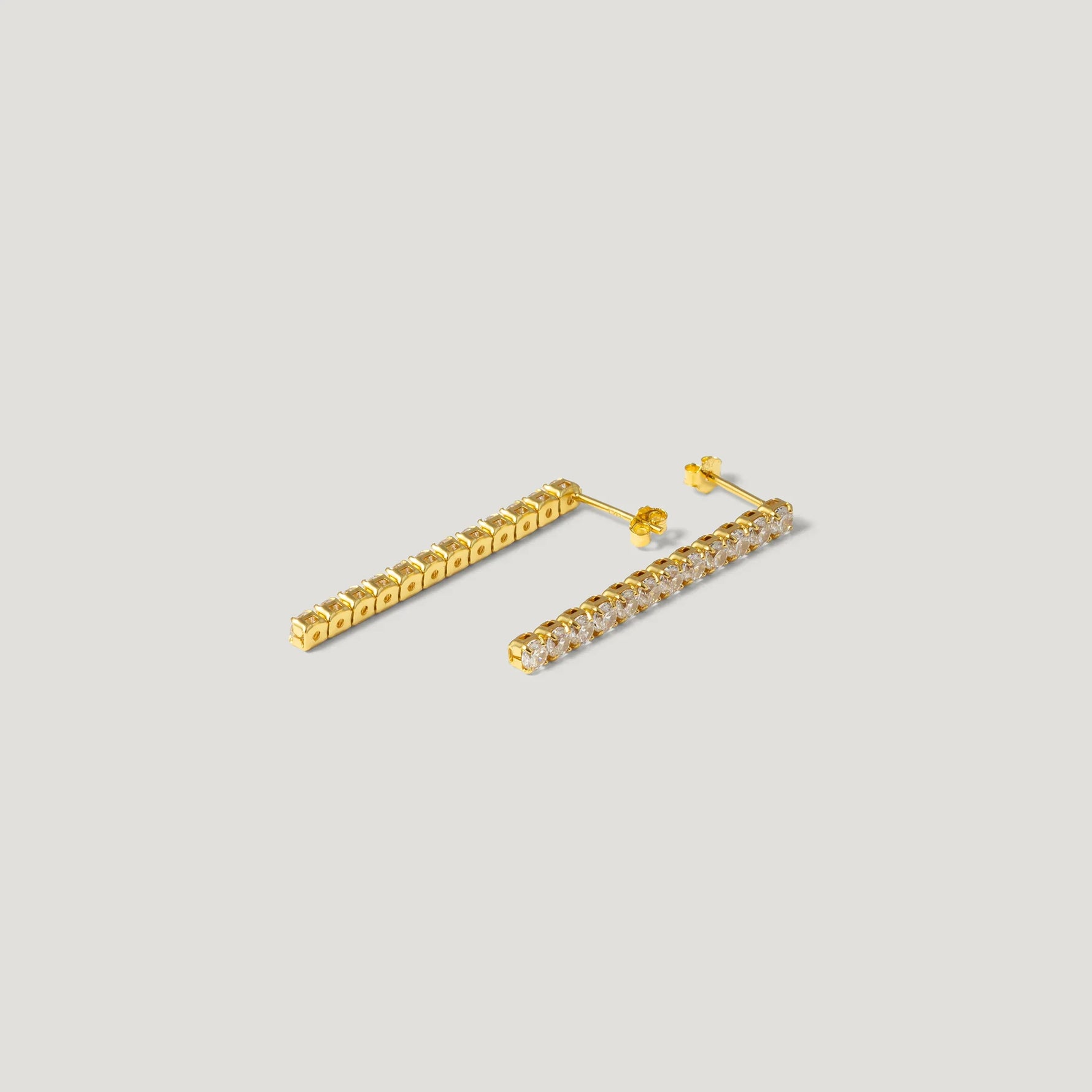 Pair of gold bar earrings with clear gemstones on light background