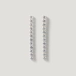 Elegant silver drop earrings with a row of sparkling round gemstones on a neutral background