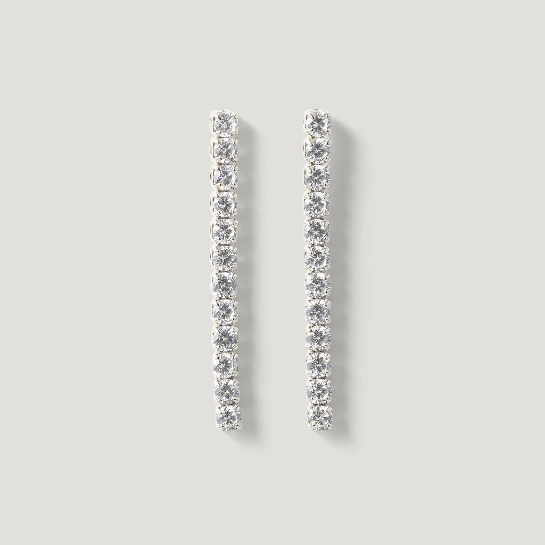 Elegant silver drop earrings with a row of sparkling round gemstones on a neutral background