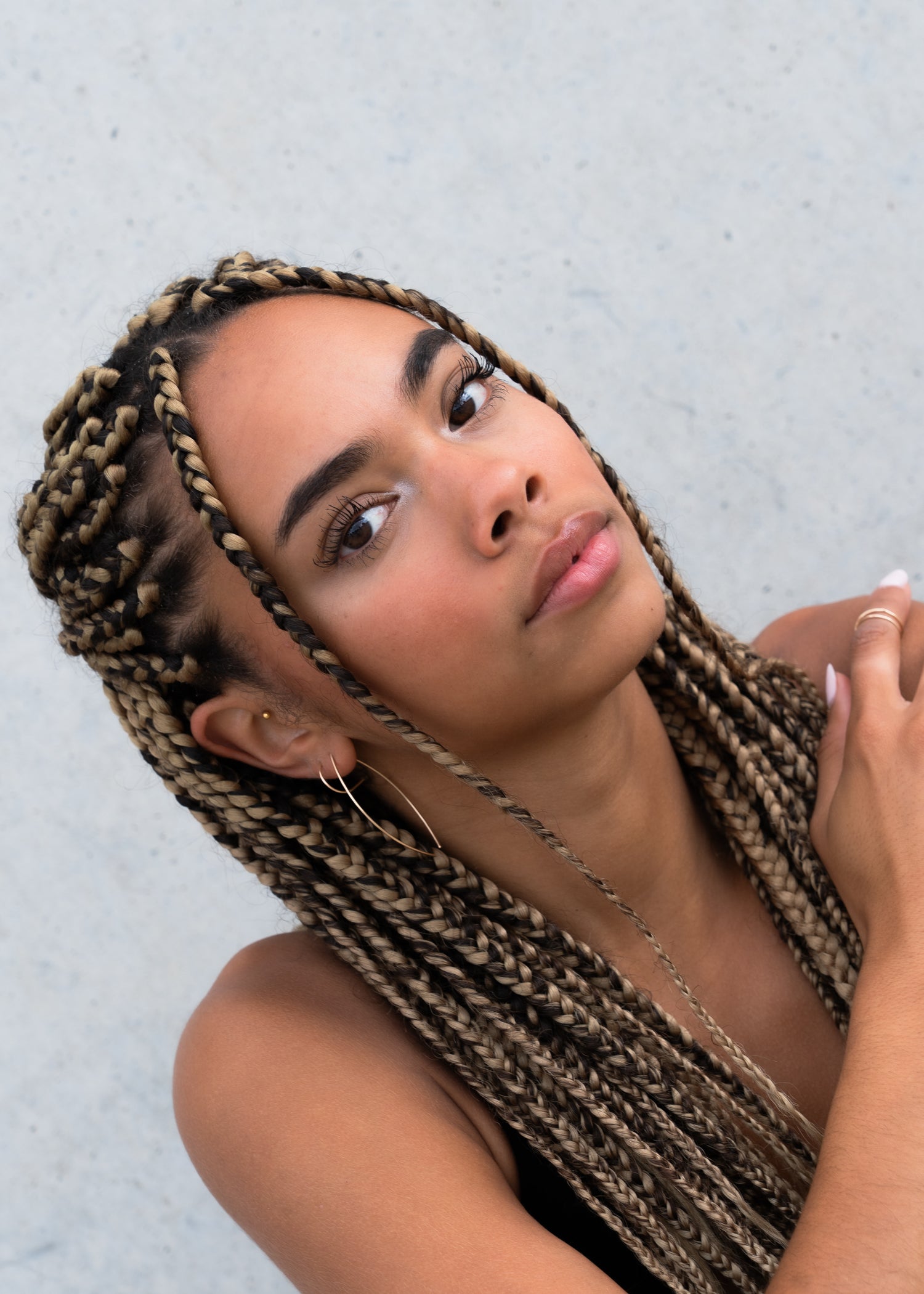 Close-up of woman with braided hair wearing a gold thread earring and stud.