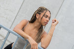 Woman with braided hair in profile wearing a gold pearl drop earring and hoop.
