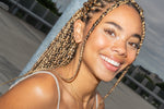 Close-up of smiling woman with multiple ear piercings, wearing a gold pearl drop earring.