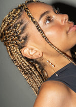 Close-up profile of an ear with multiple gold piercings and a pearl drop chain earring.